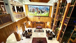 Un lobby espacioso con una zona de estar central, una gran pantalla de televisión y decoración de madera.