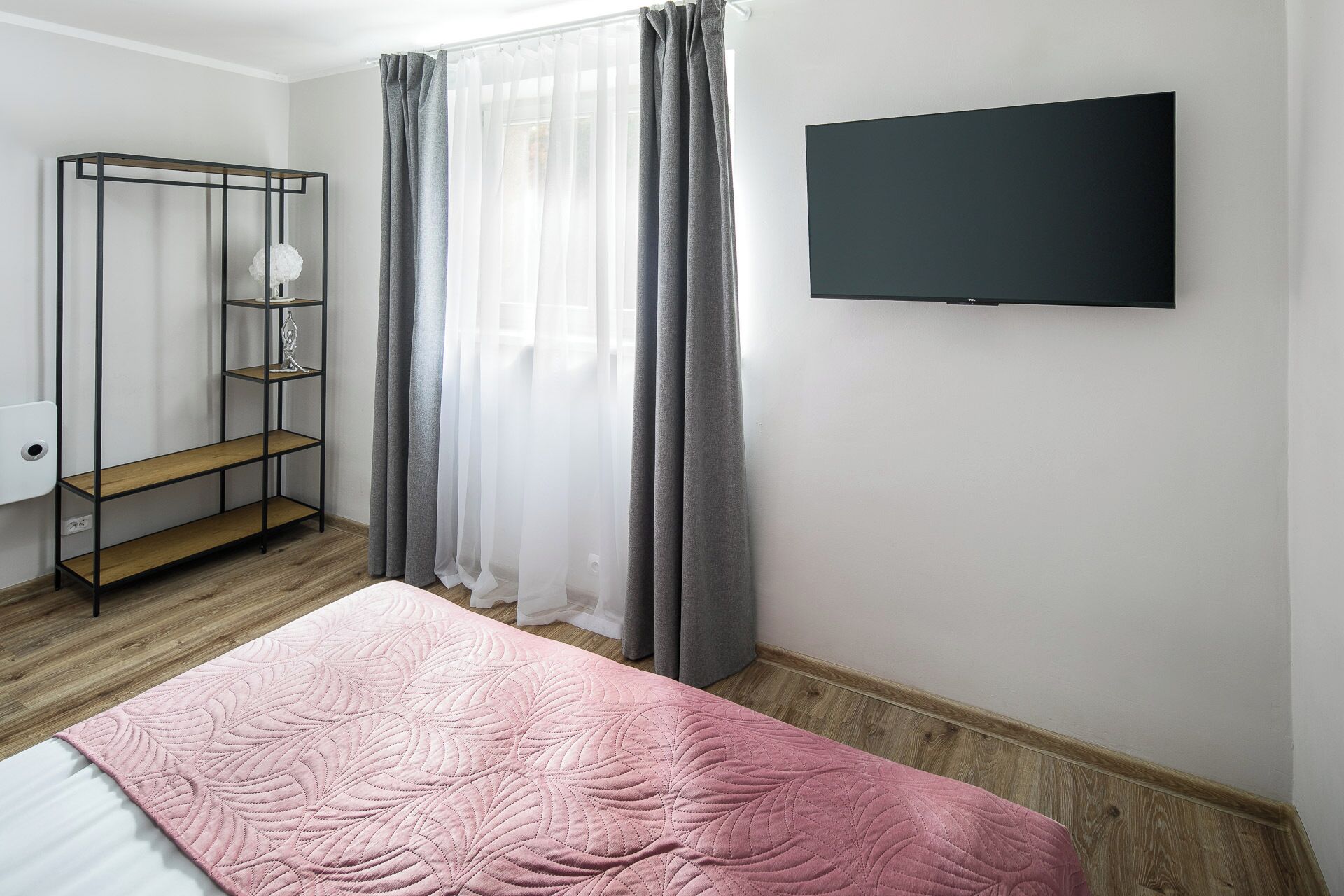 A bedroom with a bed, a TV, a wardrobe, and a window with curtains.