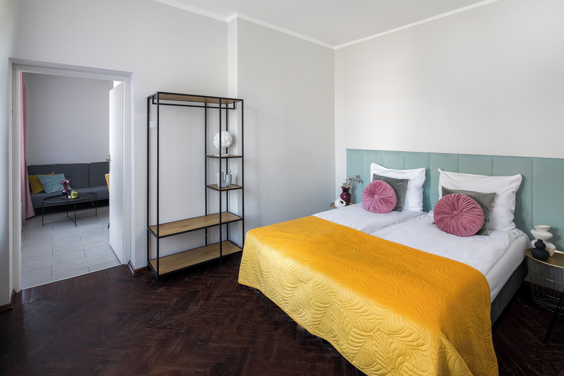 A bedroom with a bed, a nightstand, a bedside table, a wardrobe, and a small seating area with a sofa and a coffee table.