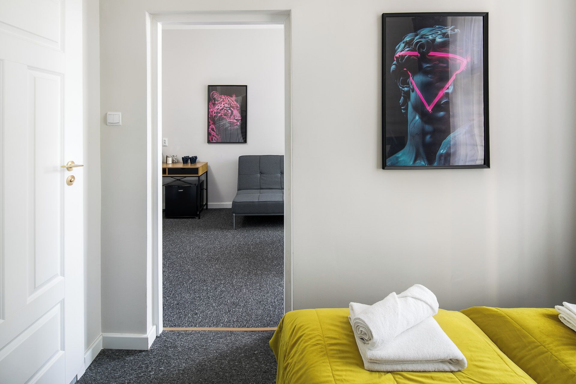 Een hotelkamer met een bed, een bureau, een stoel en twee kunstwerken aan de muur.