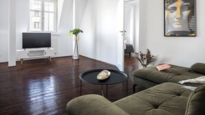 Una sala de estar moderna con una televisión de pantalla plana, una mesa de centro redonda y un sofá verde.