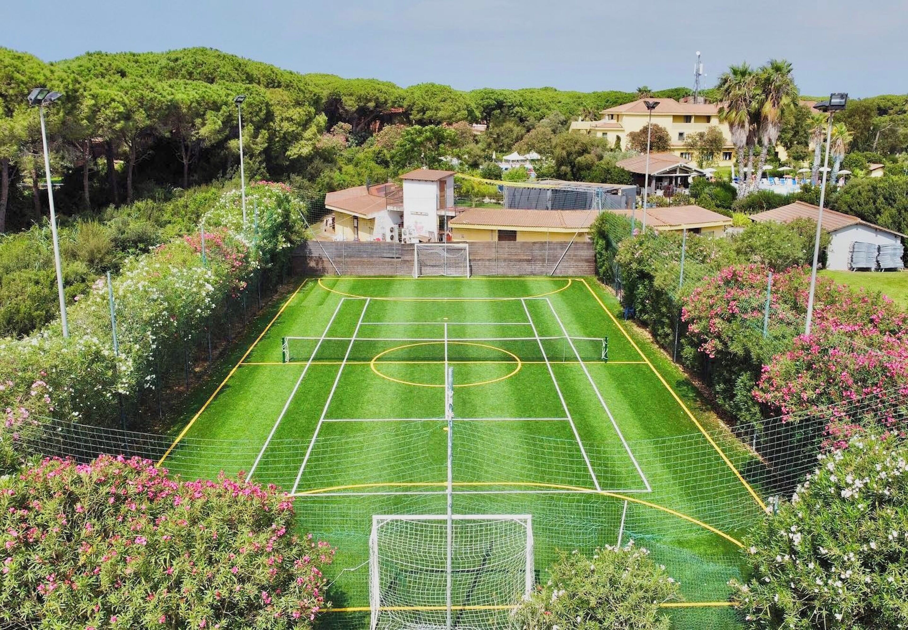 A soccer field surrounded by lush greenery and residential buildings.