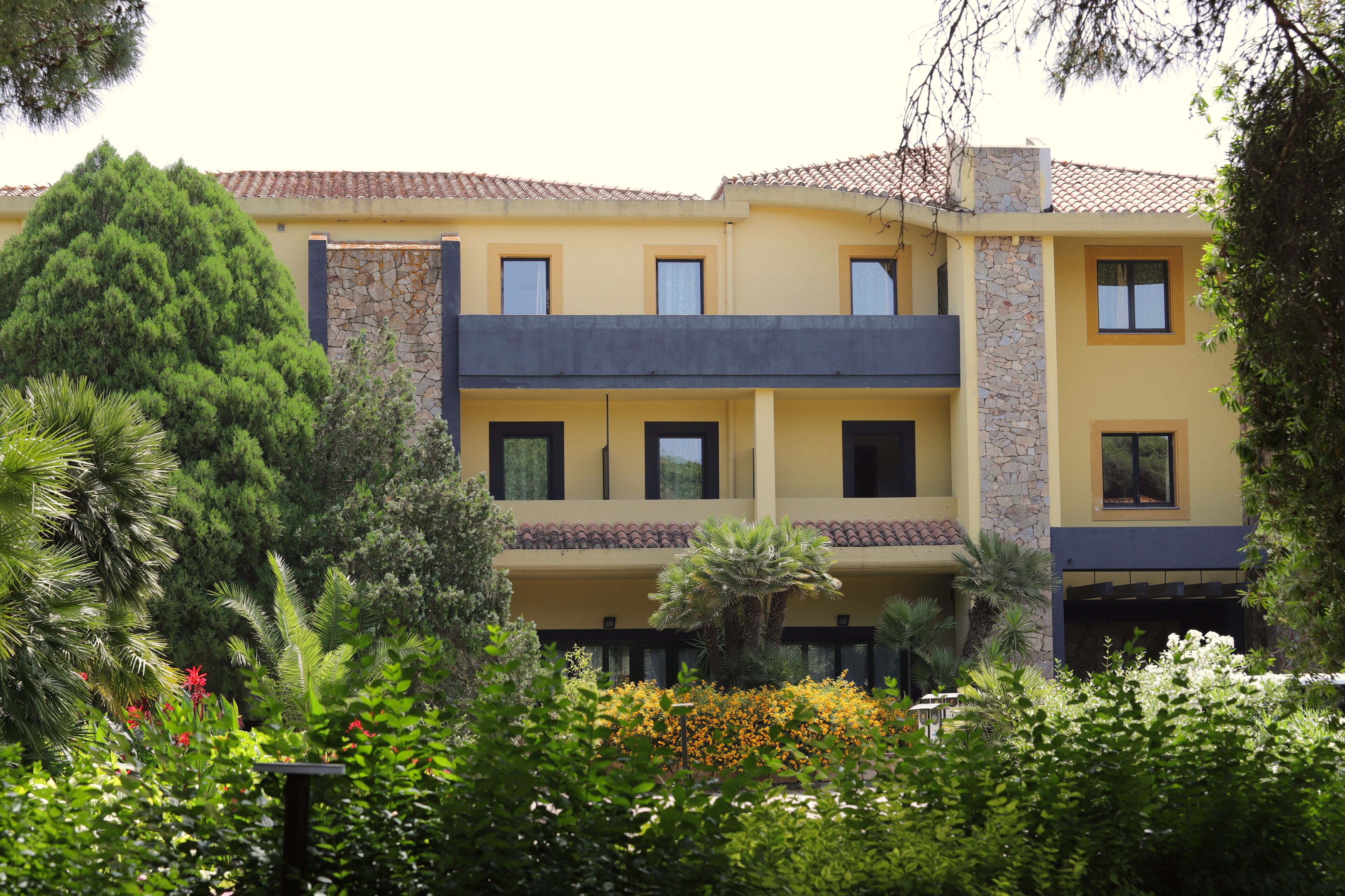 A two-story building with a yellow facade, stone accents, and multiple balconies.