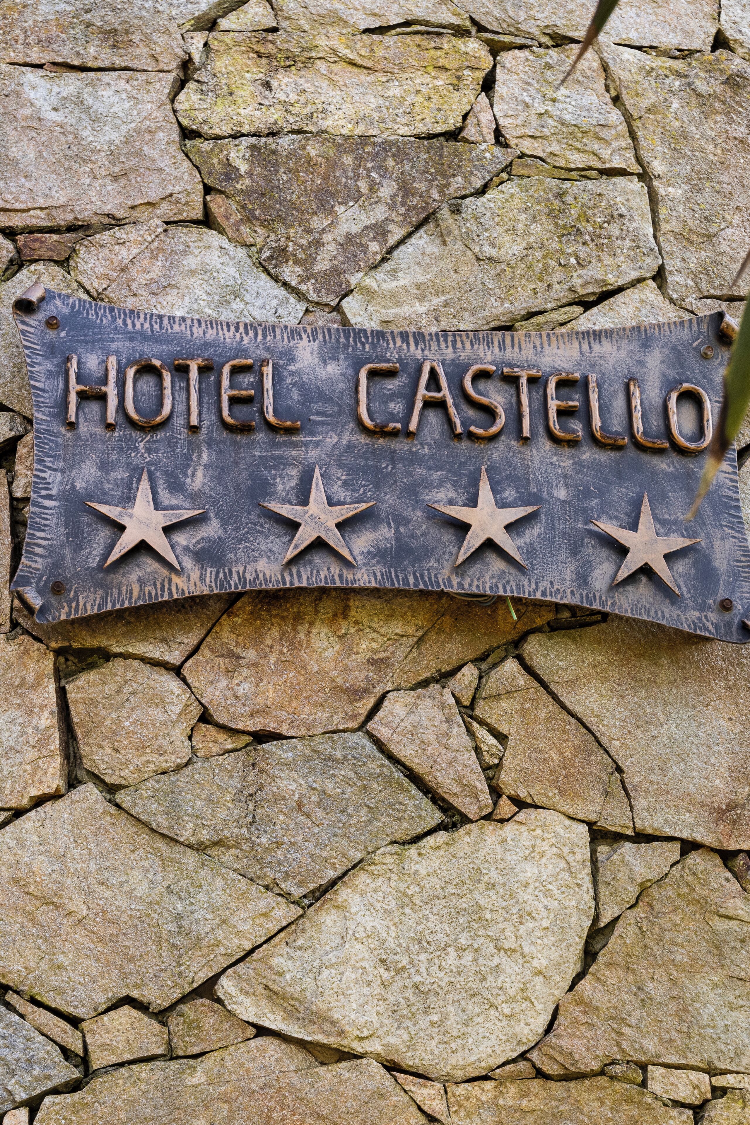 A metal sign with the text "HOTEL CASTELLO" and three stars.