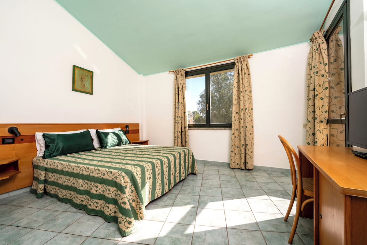 A bedroom with a bed, a desk, and a chair.
