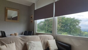 A bedroom with a bed, a desk, and a window with a view of trees. - Lovely Lodge Next To The Mansion House Llansteffan (Carmarthen)