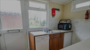A compact kitchen with a dishwasher, a microwave, and a sink. - Lovely Lodge Next To The Mansion House Llansteffan (Carmarthen)