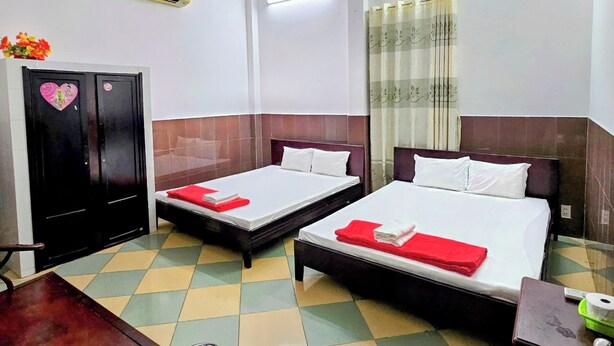 A hotel room with two beds, a desk, a chair, a wardrobe, and a ceiling fan. - Kien An Hotel (Can Tho)