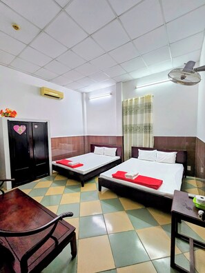 A hotel room with two beds, a desk, a chair, a wardrobe, and a ceiling fan. - Kien An Hotel (Can Tho)