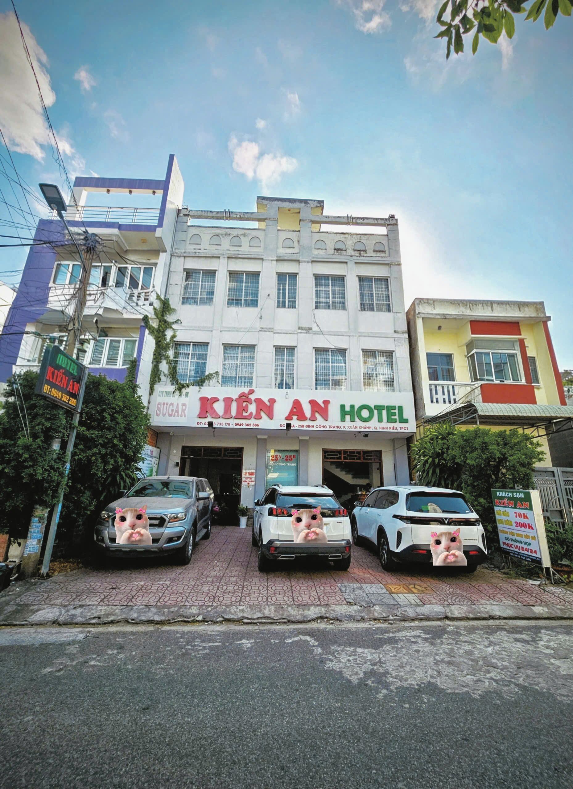 A hotel with a signboard, multiple cars parked in front, and a clear sky.