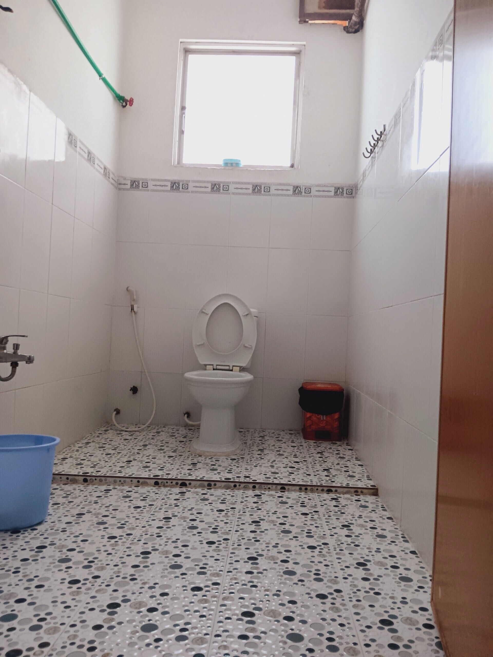 A small bathroom with a toilet, a shower, and a window.