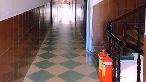 A hallway with a checkered floor, a staircase on the right, and a door at the end. - Kien An Hotel (Can Tho)