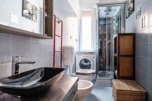 A modern bathroom with a black vessel sink, a washing machine, and a shower area. - Porta Mascarella Apartment by Wonderful Italy (Bologna)
