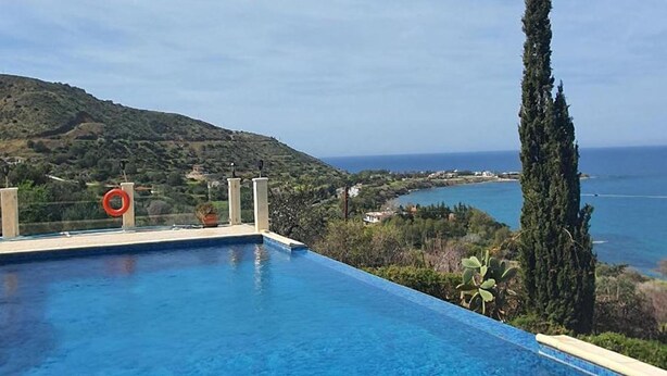 A clear blue swimming pool with a view of a coastal landscape and a hill in the background. - Villa Aquavitus in Pachyammos (Pomos)