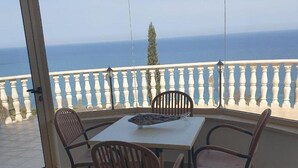 A balcony with a table and chairs, overlooking a body of water. - Villa Aquavitus in Pachyammos (Pomos)
