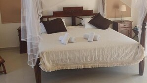 A four-poster bed with a canopy, a wooden headboard, and a nightstand with a lamp. - Villa Aquavitus in Pachyammos (Pomos)