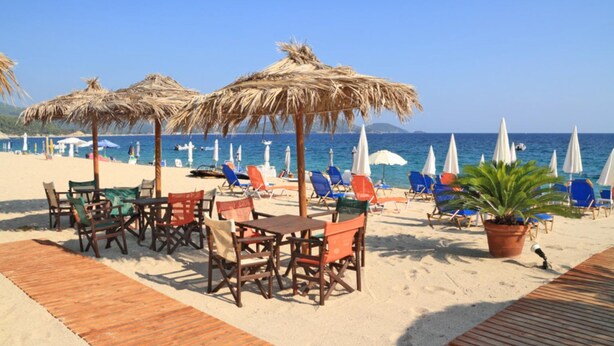 A beachside restaurant with outdoor seating, umbrellas, and a view of the sea. - Villa River View in Peristerona (Peristerona)