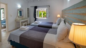 Une chambre avec deux lits, un bureau, un miroir et une fenêtre donnant sur un paysage verdoyant.