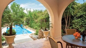 Un patio con piscina, mobiliario exterior y abundante vegetación.