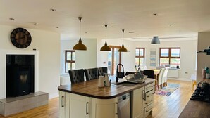 Une cuisine moderne dotée d’un îlot central, de luminaires suspendus et d’un lave-vaisselle encastré.