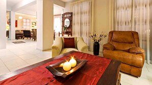 A living room with a sofa, a recliner, a coffee table with candles, and a mirror on the wall. - Villa Irene Palace in Peristerona (Peristerona)