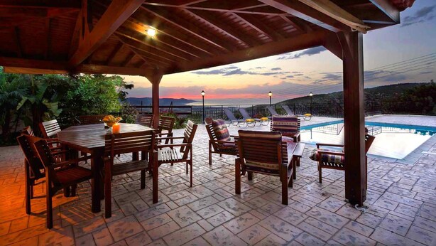 An outdoor patio with a wooden pergola, a pool, and a view of the landscape. - Villa Irene Palace in Peristerona (Peristerona)