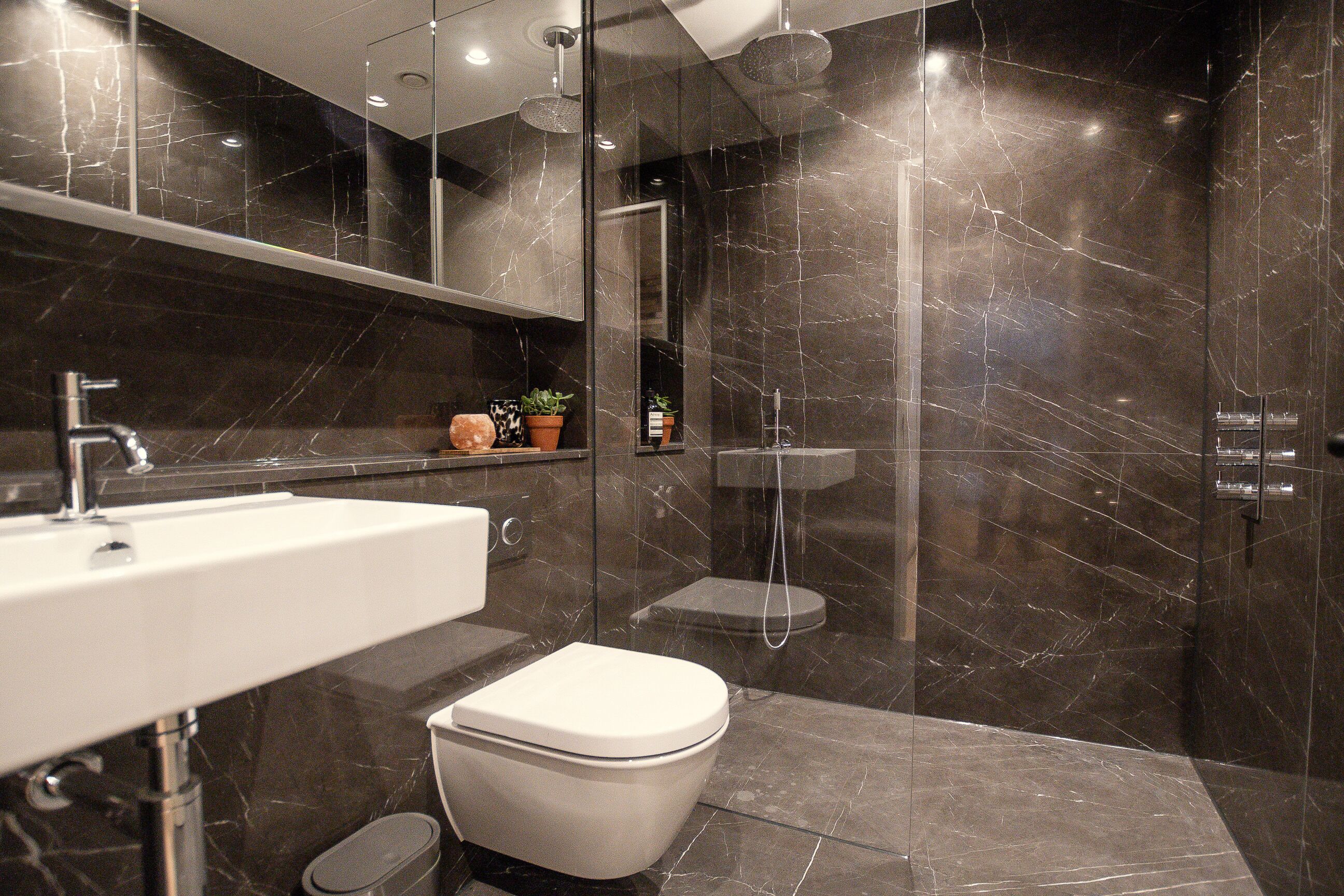 A modern bathroom with a white sink, toilet, and shower.