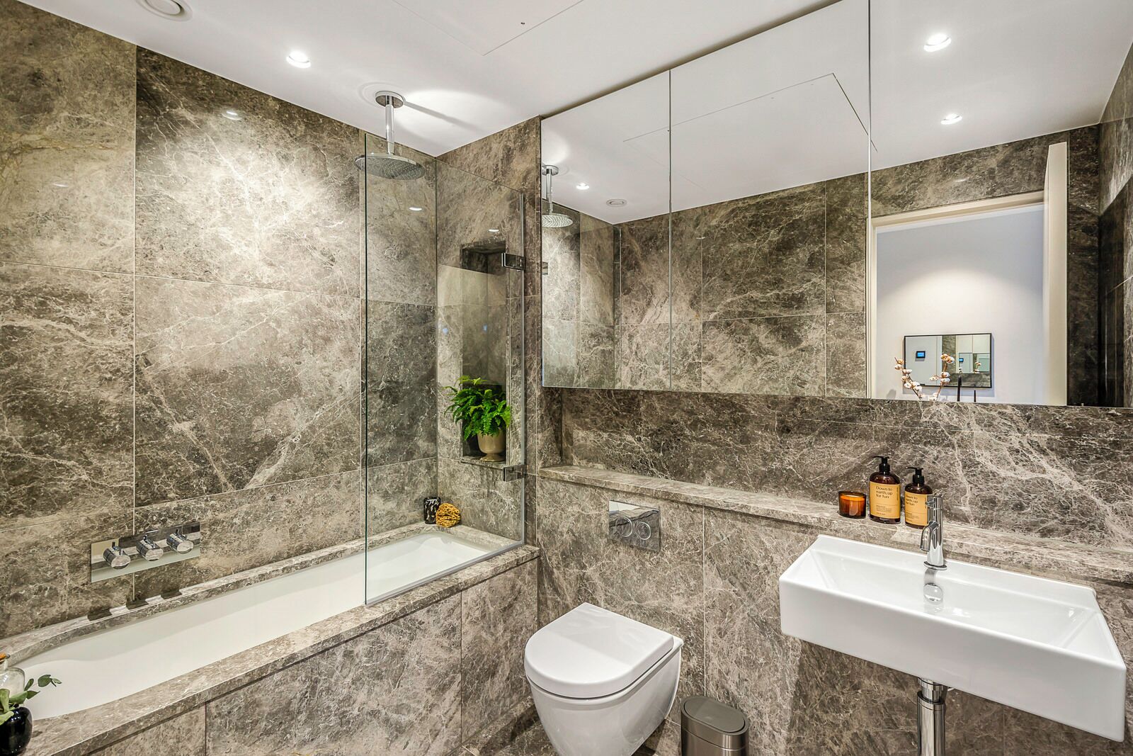 A modern bathroom with a glass-enclosed shower, a white sink, and a toilet.