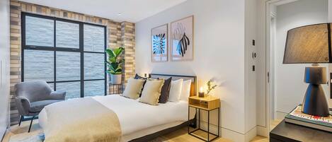 Une chambre moderne avec un grand lit, une table de chevet avec une lampe, une chaise et une grande fenêtre donnant sur un beau paysage.