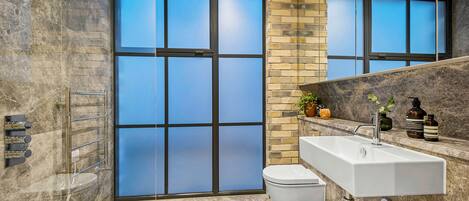 A modern bathroom with a large glass door, a white sink, and a toilet.