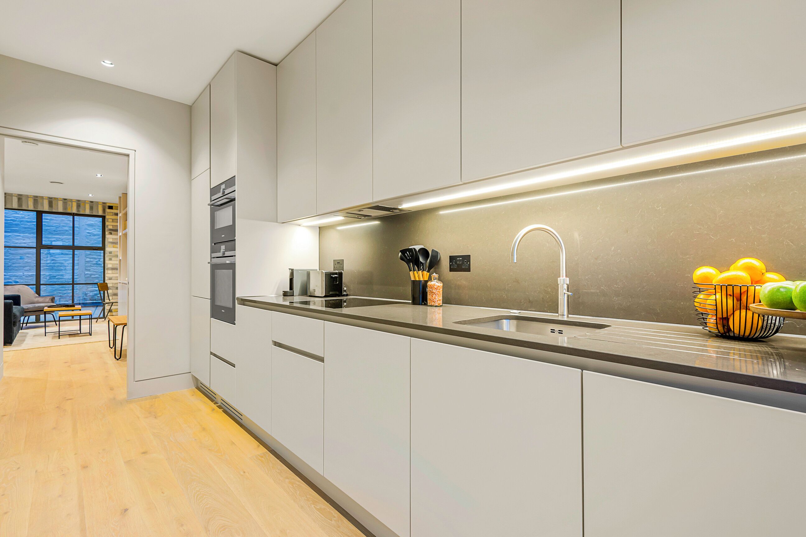 A modern kitchen with a large island, stainless steel appliances, and a view to the living area.