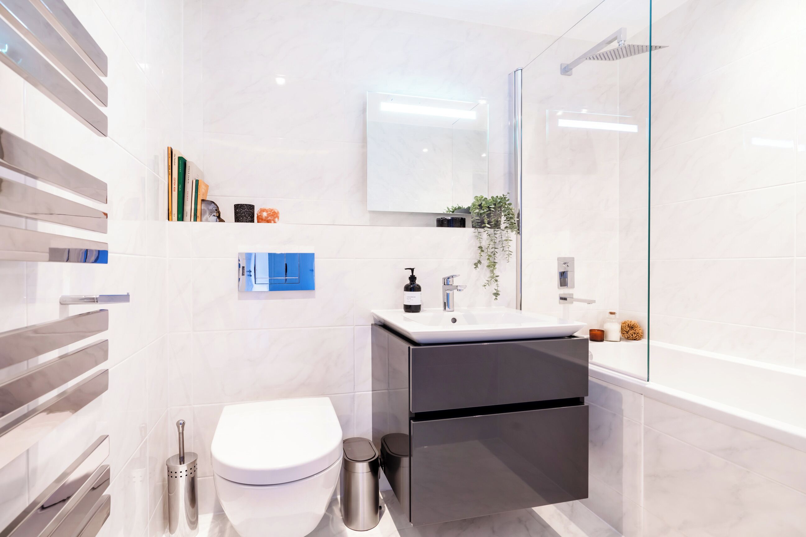A modern bathroom with a white toilet, a sink with a mirror above it, and a shower area.