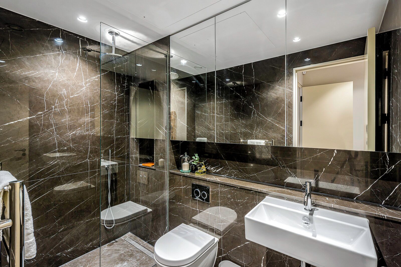 Un bagno moderno con doccia vetrata, un water bianco e un lavandino capiente.