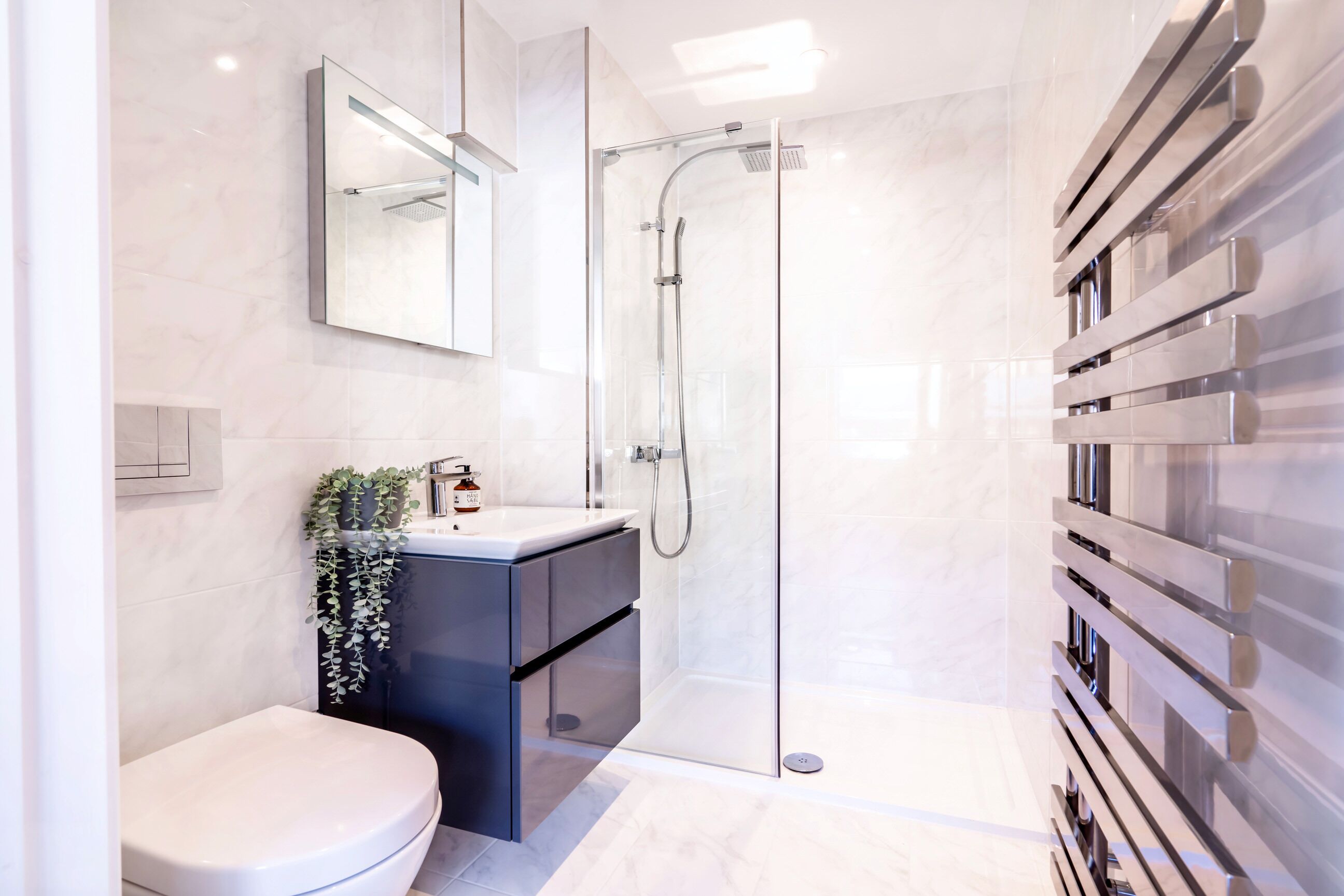 A modern bathroom with a glass-enclosed shower, a white toilet, a dark vanity, and a wall-mounted towel rack.