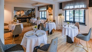 Ein Essbereich mit runden Tischen, Stühlen und einer Bar im Hintergrund.
