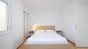 Un dormitorio minimalista con una cama de madera, dos mesitas de noche y una puerta con picaporte.