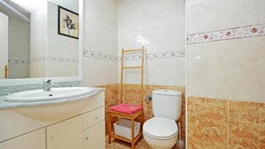 Un baño con lavamanos, inodoro y una escalera de madera.