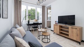 A modern living room with a sofa, TV stand, and dining area. - Stylish Apartment with Balcony | 2 Bedrooms | Parking. (Kraków)