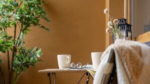 A small, cozy room with a wooden chair, a table, a potted plant, and a lamp. - Stylish Apartment with Balcony | 2 Bedrooms | Parking. (Kraków)