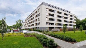 A multi-story residential building with a flat roof and a symmetrical facade. - Stylish Apartment with Balcony | 2 Bedrooms | Parking. (Kraków)