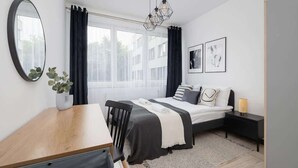 A modern bedroom with a bed, bedside table, and a desk. - Stylish Apartment with Balcony | 2 Bedrooms | Parking. (Kraków)