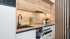 Une cuisine moderne avec des meubles de rangement en bois, un robinet noir, un ananas posé sur le plan de travail et une machine à café.