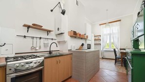Cocina compacta con estufa, pileta y armarios de madera. Hay una pequeña isla con microondas y una silla.