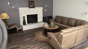 A living room with a fireplace, a leather sofa, a lamp, and a rug.