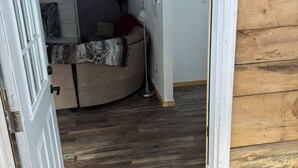 A room with a bed, a lamp, and a wooden floor.
