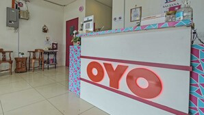 A reception desk with the name "OYO" prominently displayed, a tiled floor, and a few chairs and tables in the background. - OYO 90999 DG HOTEL (Sungai Petani)