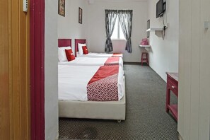 Quarto de hotel com duas camas, televisão, pequena mesa de escritório e janela com cortinas.