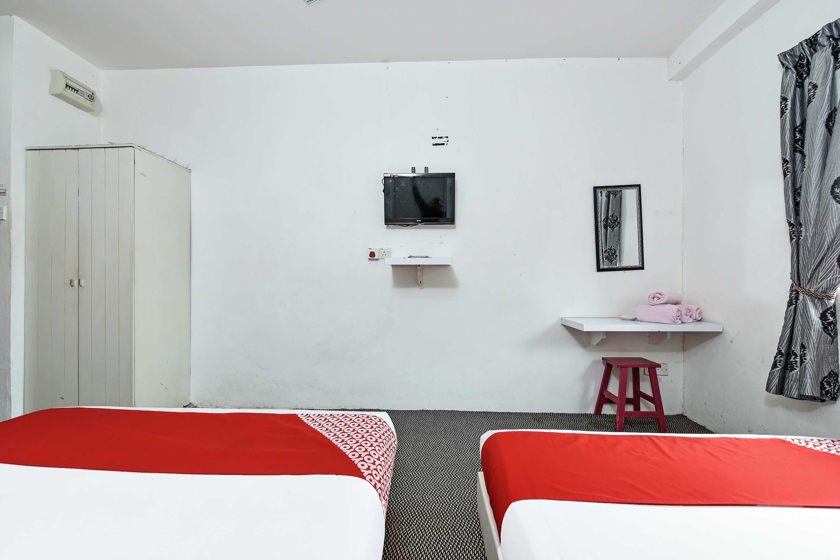 A room with two beds, a small desk, a mirror, and a wardrobe.