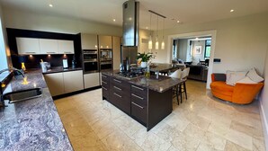 Una cocina moderna con una isla central, electrodomésticos integrados y un comedor con sofá.