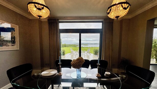 Un comedor con una mesa de vidrio, sillas negras y dos candelabros.